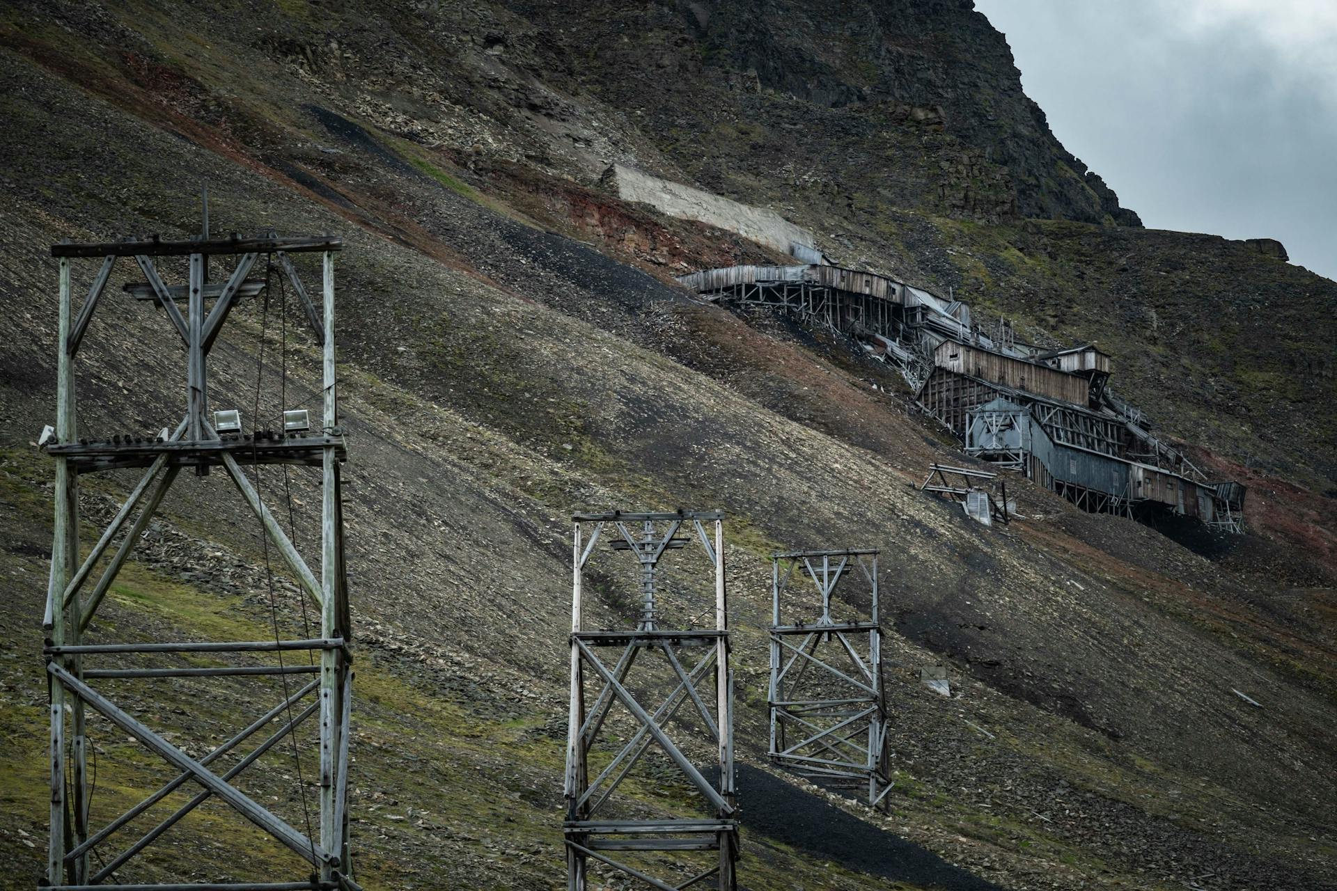 Old mining structures on a rugged mountain slope, showcasing industrial decay.