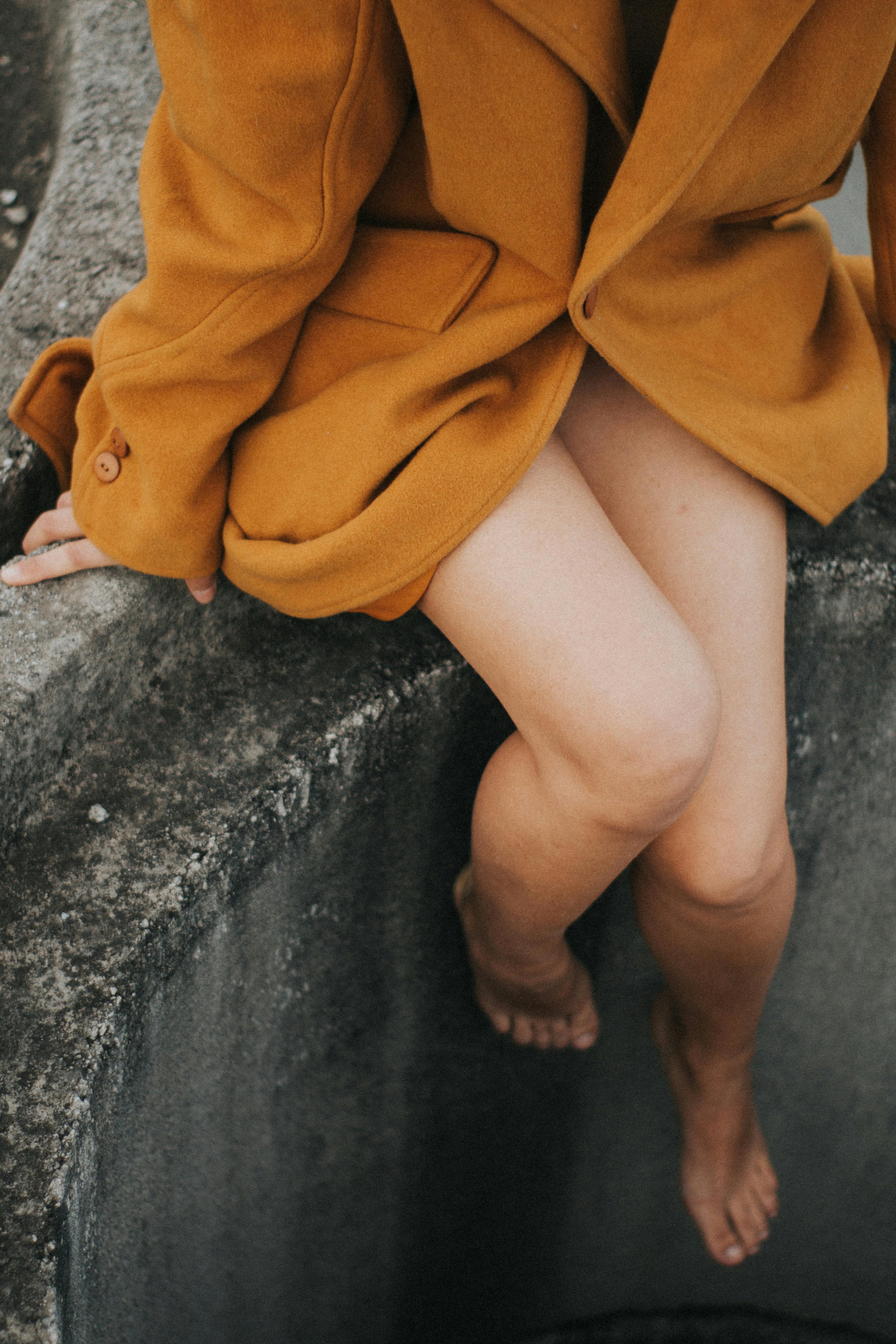 Woman Wearing Brown Coat Sits on Top of Culvert