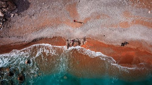 Free Stunning aerial shot of turquoise waves meeting a rocky beach shoreline, capturing scenic beauty from above. Stock Photo