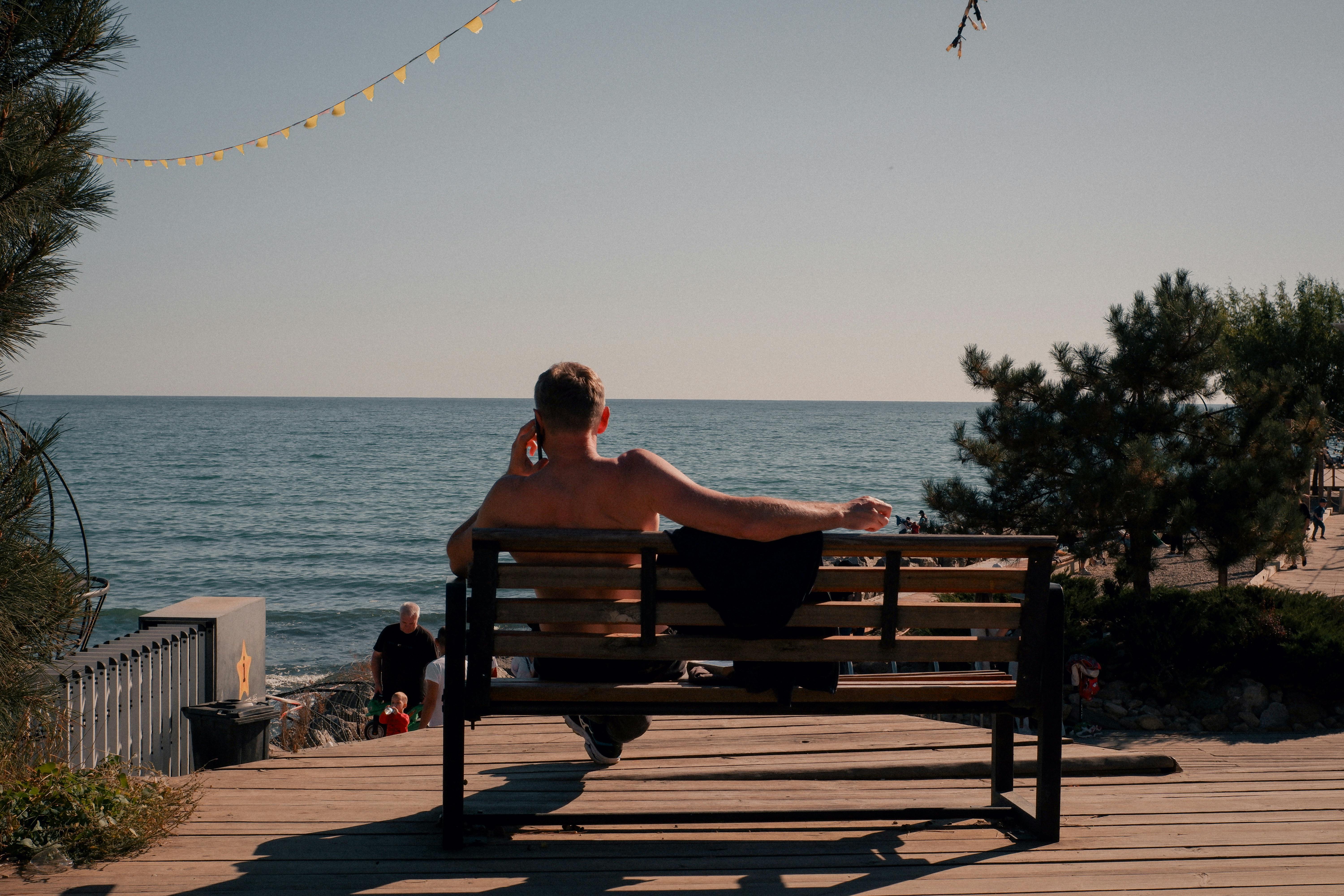 A man sitting on a bench enjoying a peaceful summer sunset by the sea in Odessa, Ukraine.