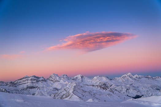 Breathtaking sunrise over snowy Pyrenees mountains in Laruns, France with dramatic cloud formations.