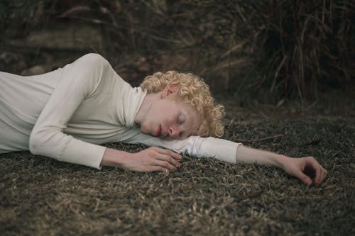 бесплатная Женщина в топе с длинными рукавами и водолазкой, лежа на траве Стоковое фото