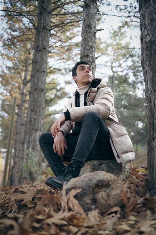 Man in a Jacket Sitting on a Rock in the Forest