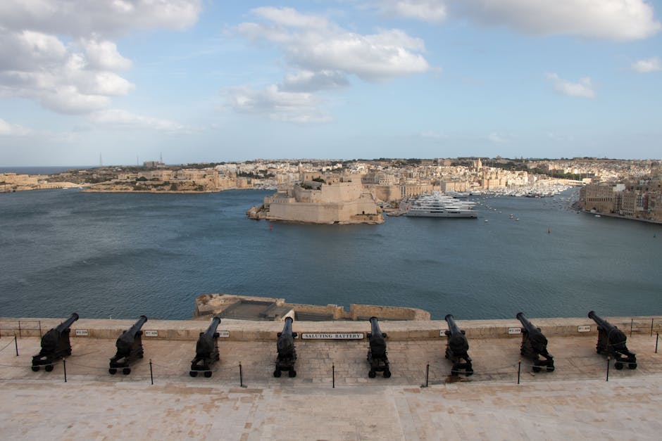 Panoramic view of Valletta's Grand Harbour with historic cannons in the foreground, Malta.