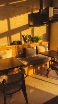 Warm, inviting indoor seating area with elegant shadows and cozy decor, illuminated by soft sunlight.