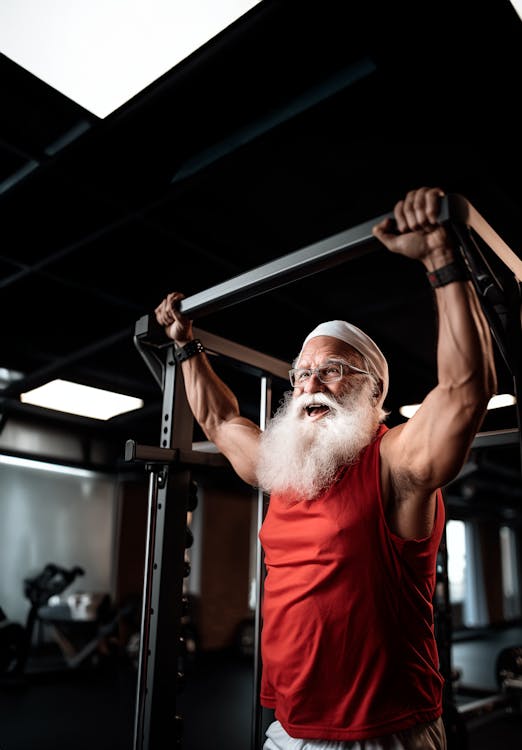 Fit Santa at the gym wearing red tank top doing exercise