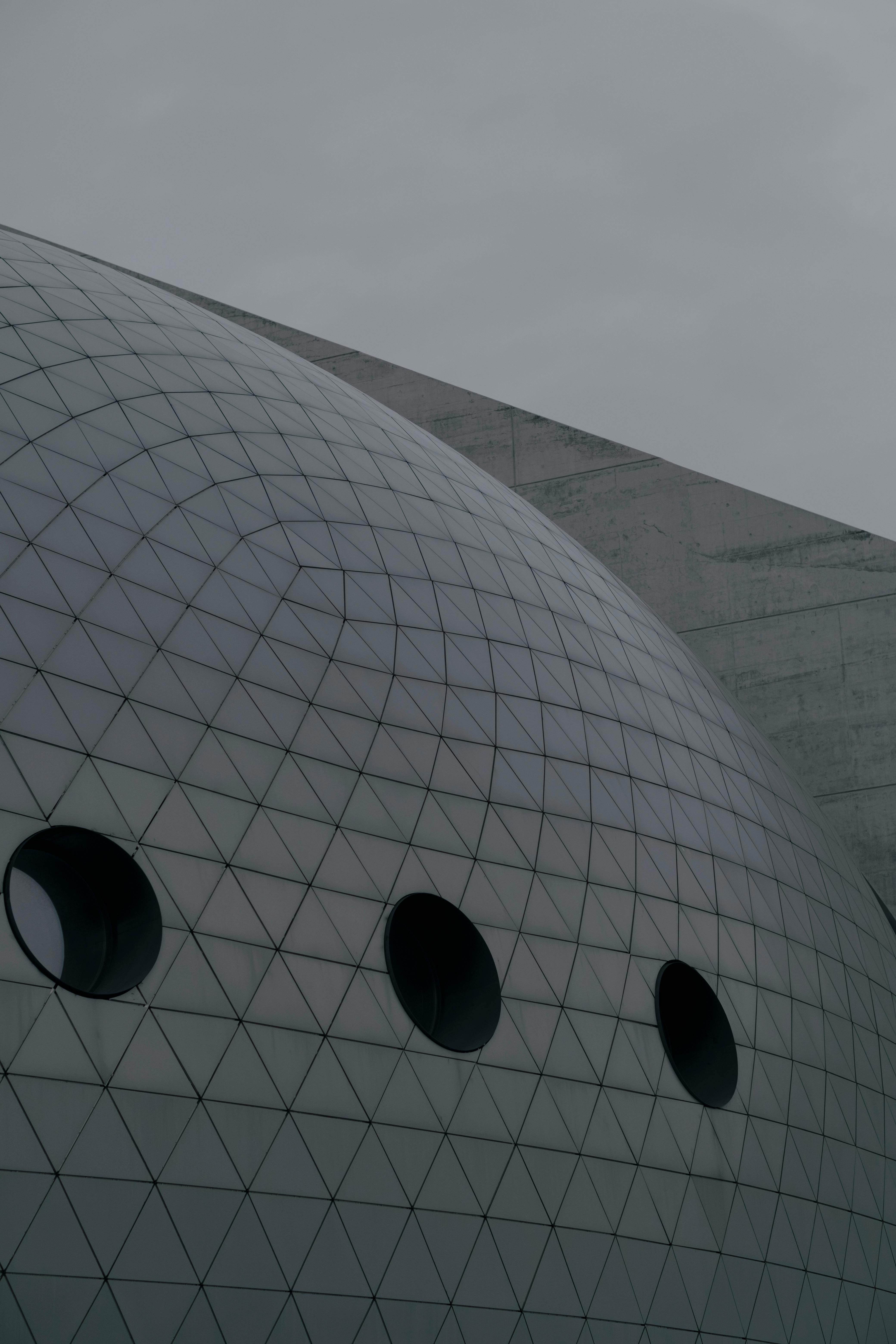 Modern architectural design featuring a futuristic dome with circular windows and geometric patterns.