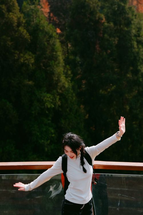 Free A joyful woman dances on a scenic mountain bridge with lush forest backdrop, embracing nature's beauty. Stock Photo