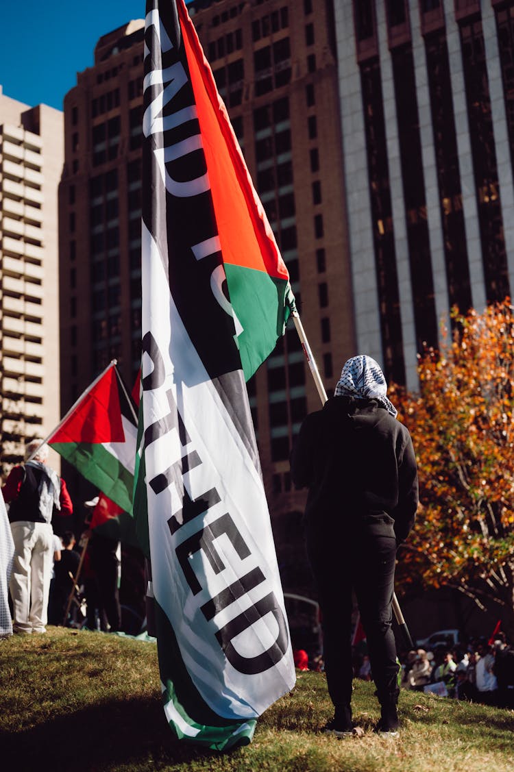 Person Wearing Kufiya Holding Palestine Flag