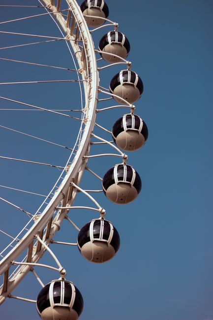 A close-up of a Ferris wheel's gondolas against a clear blue sky, showcasing the engineering design.