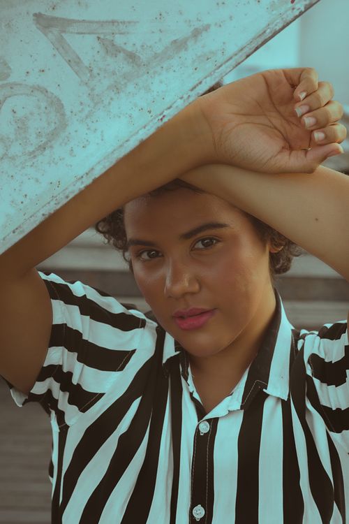 Free Portrait of a young woman in a striped shirt posing outdoors with a casual expression. Stock Photo