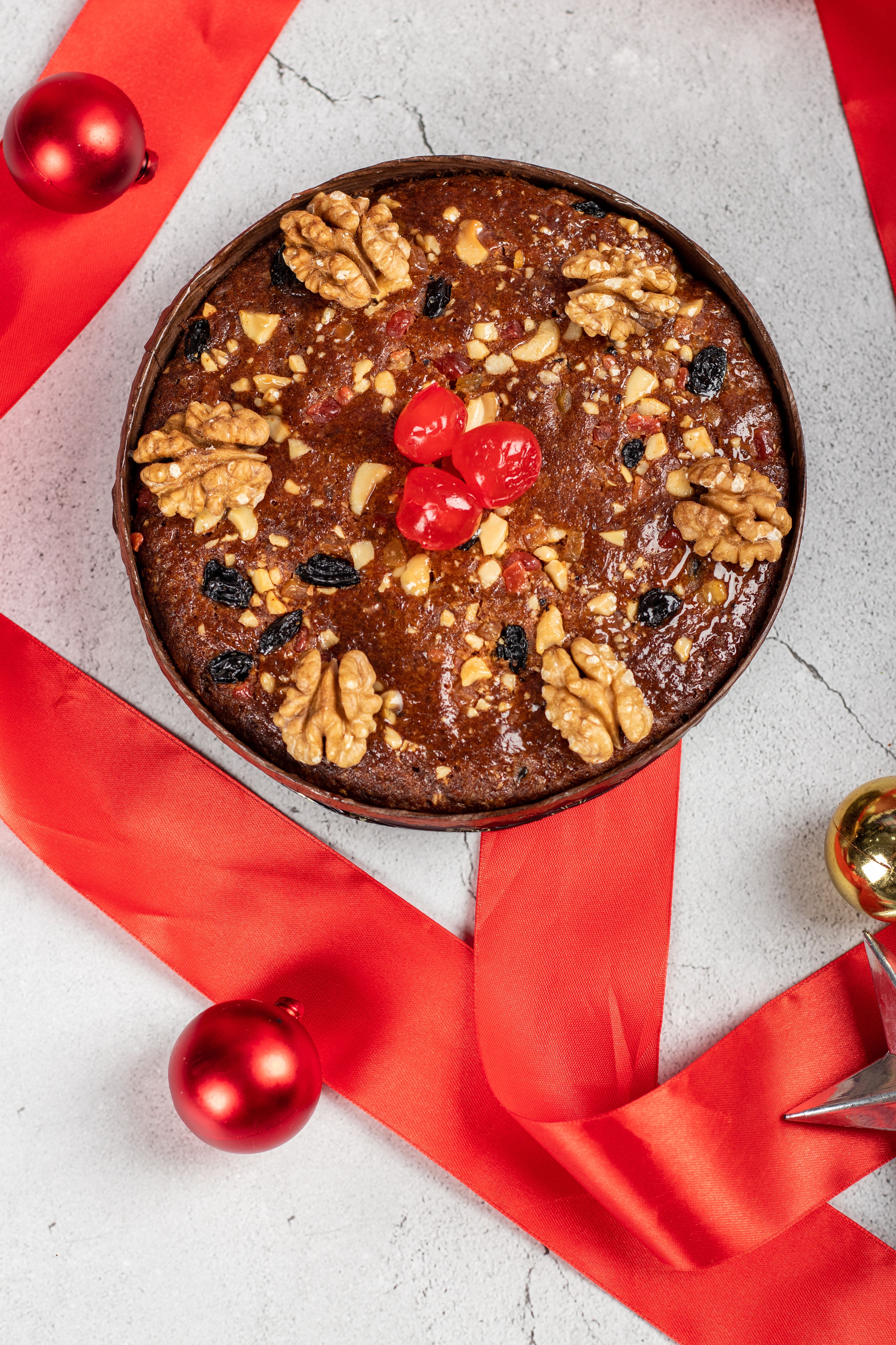 Delicious fruitcake adorned with walnuts and cherries, captured in a top view with a festive Christmas theme.