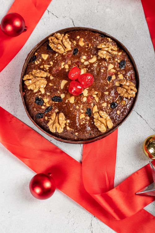 Free Delicious fruitcake adorned with walnuts and cherries, captured in a top view with a festive Christmas theme. Stock Photo
