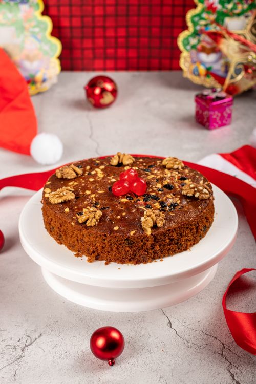 Free Delicious chocolate cake with walnuts and cherries on a cakestand, surrounded by Christmas decorations. Stock Photo