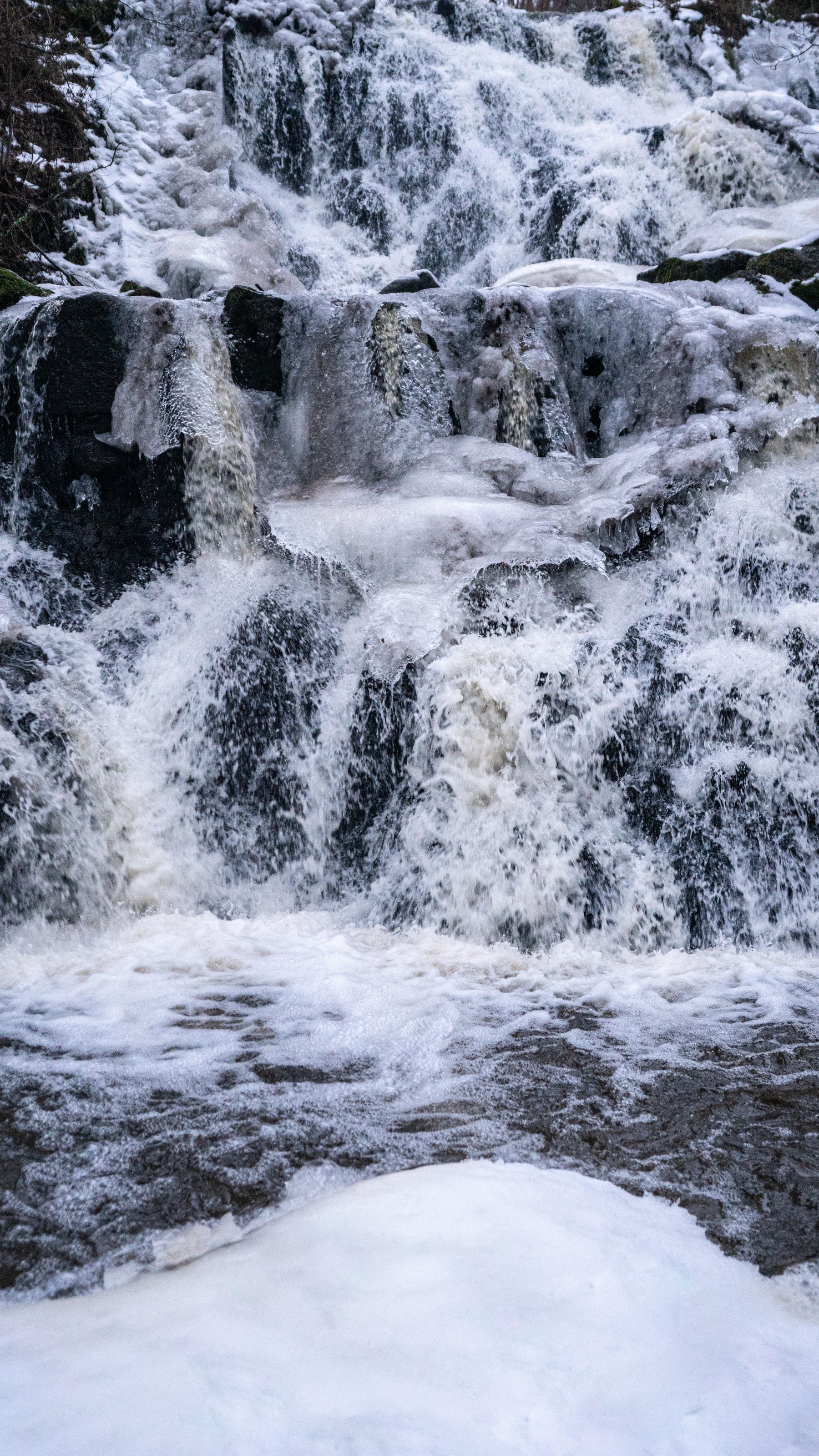 Cascade turquoise entre glace et rochers en hiver