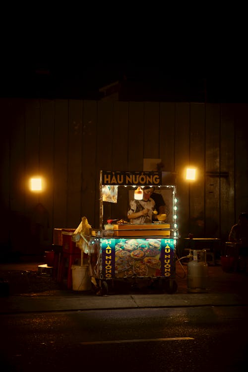 Man Selling Food in a Booth at Night 