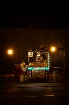 A bustling street food stall lit up at night, offering a vibrant atmosphere in an urban setting.