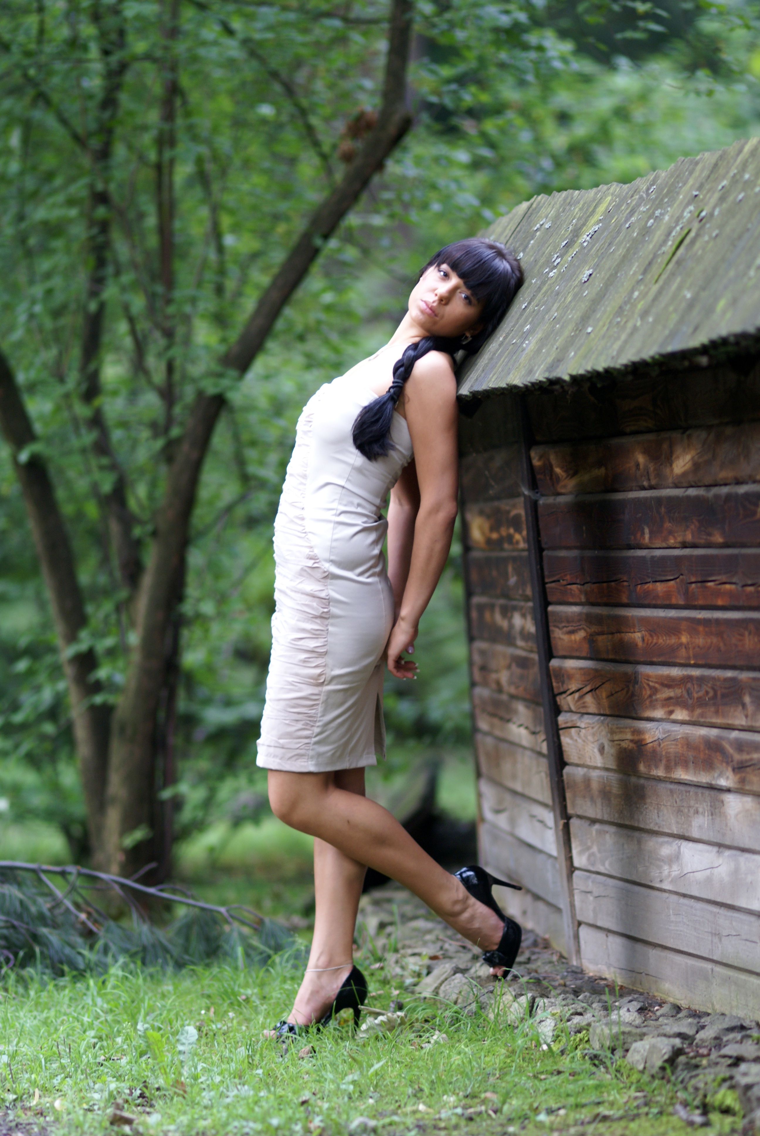 A woman in a dress leaning against a wooden wall · Free Stock Photo