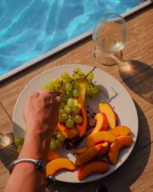 Woman Hand over Plate of Fruit