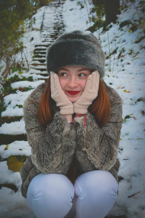 Beautiful Woman in Fur Coat Sitting on Stairs in Winter