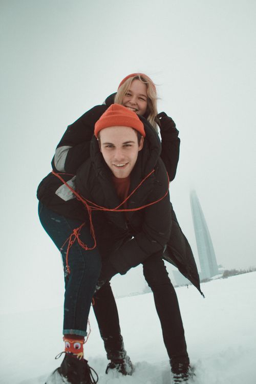 Free Low angle of happy young boyfriend piggybacking cheerful smiling girlfriend while spending winter weekend together Stock Photo
