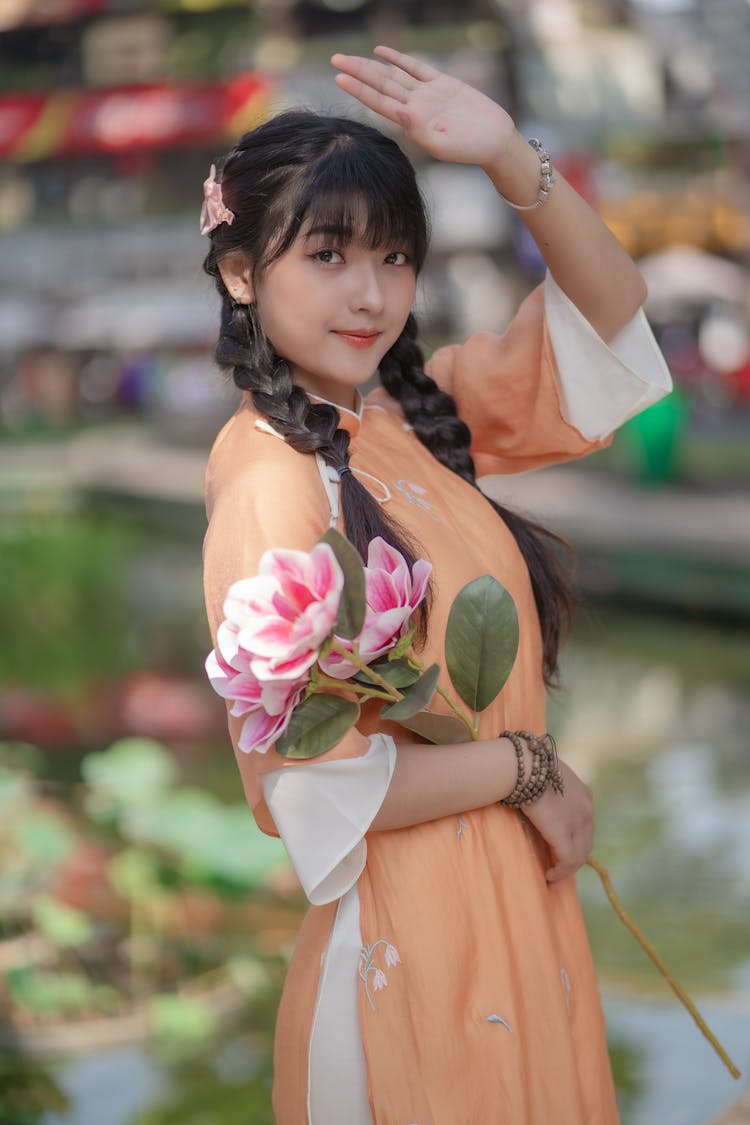 Young Model In Orange Ao Dai Holding Pink Flowers