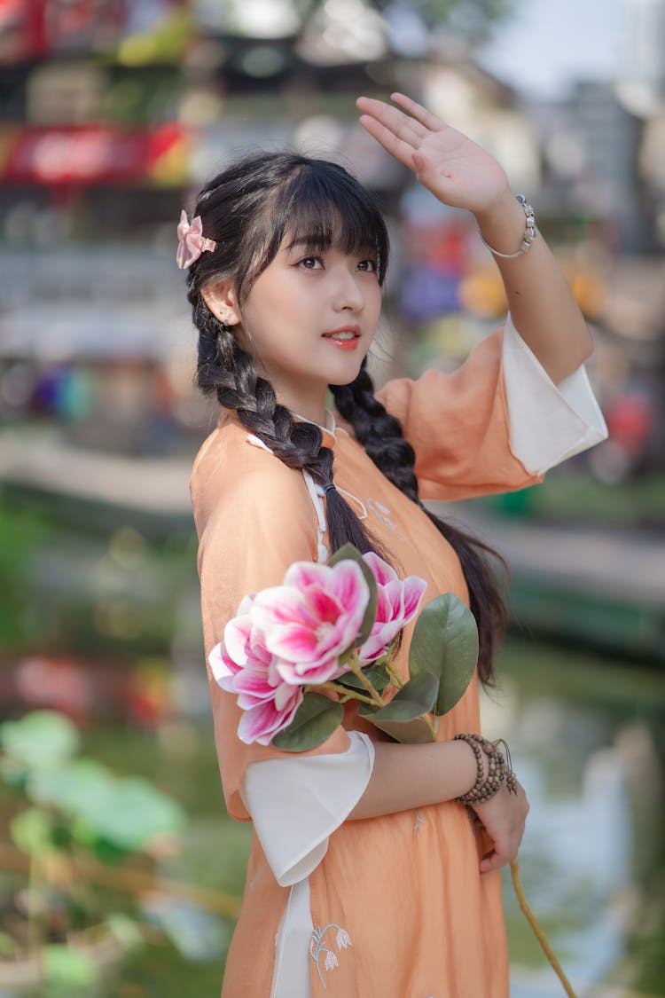 Model In Orange Long Split Ao Dai Tunic With A Bouquet Of Flowers