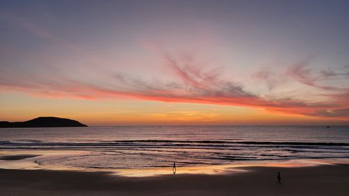 Free Stunning sunset at the beach with vibrant clouds reflecting in the ocean waves. Stock Photo