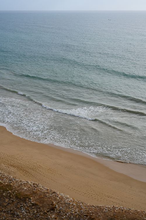 Free A peaceful aerial view of the Faro coastline, showcasing gentle waves and sandy shores in Portugal. Stock Photo