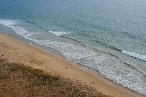 Free Stunning aerial view of Faro beach with waves crashing and few people walking on the sand. Stock Photo