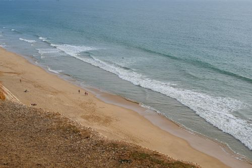 Free Drone shot capturing the serene coastline of Faro Beach, Portugal. Stock Photo