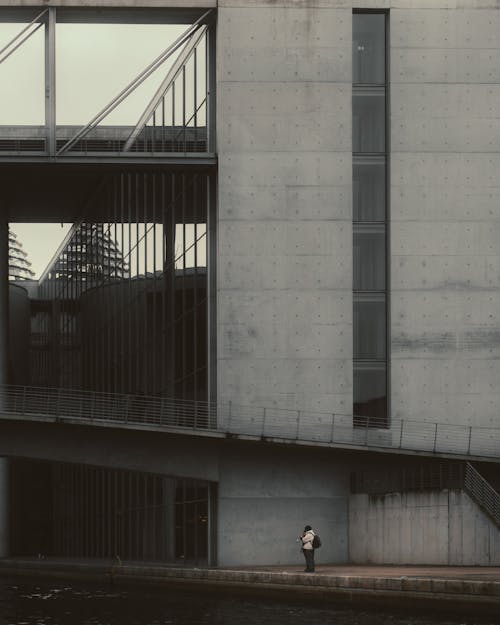 Person Standing in Front of a Large Grey Building