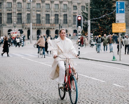 A woman cycles through Dam Square in Amsterdam, capturing urban life and transportation.