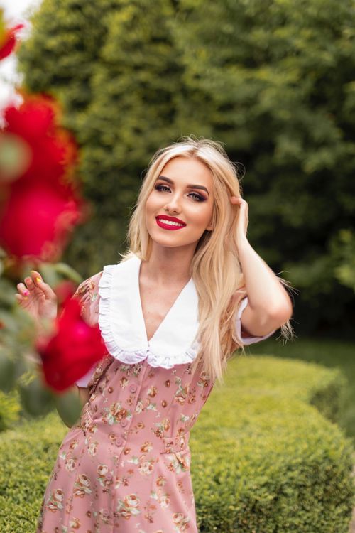 Free Blonde woman in a floral dress enjoying a sunny day in a lush park. Stock Photo