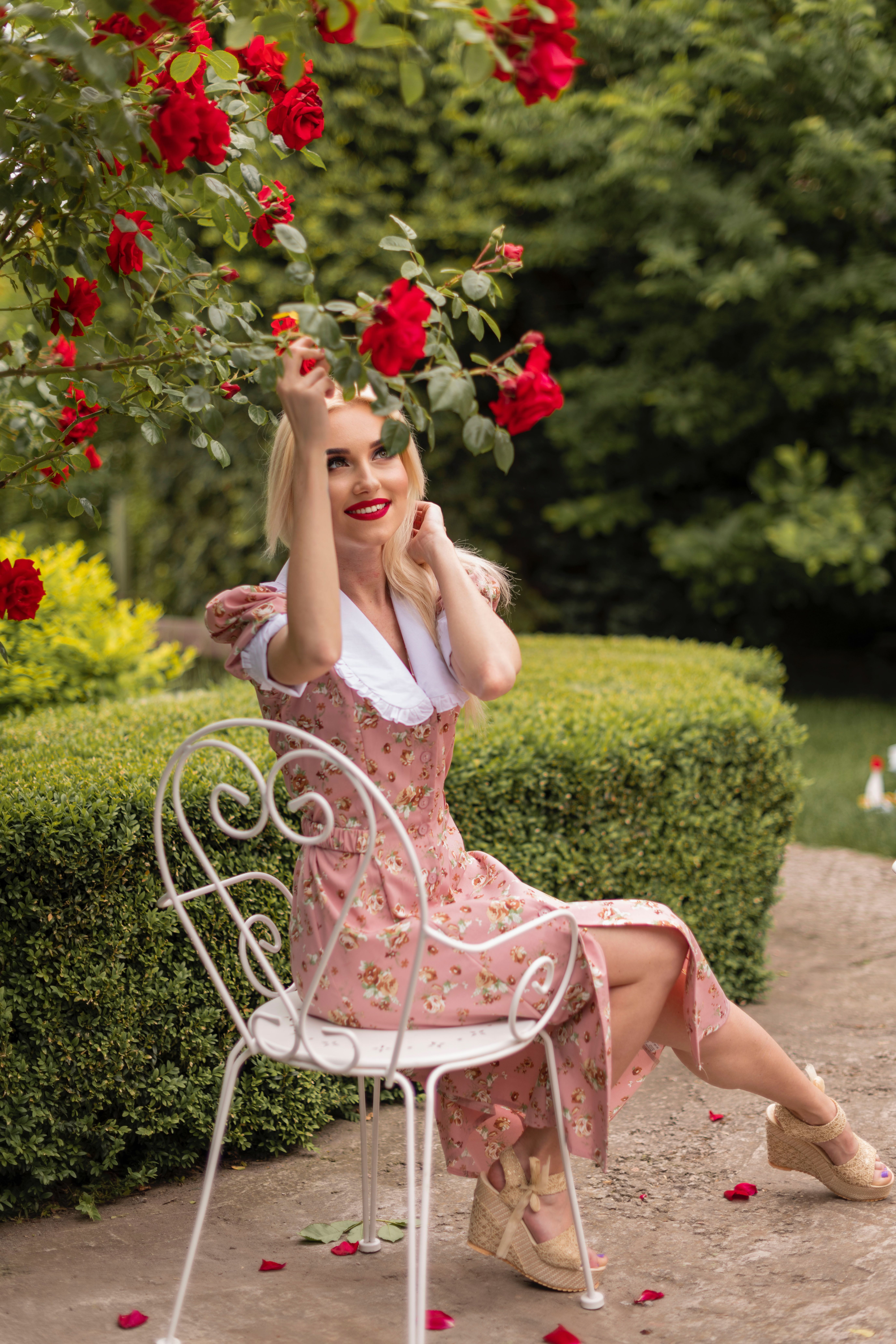 A woman in a pink dress sitting on a white chair · Free Stock Photo
