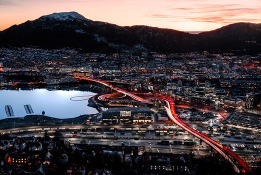 Stunning aerial view of Bergen cityscape with vibrant sunset and city lights reflecting on the water.