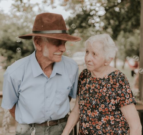 Free An endearing elderly couple sharing a joyful moment outdoors with bubbles in the air. Stock Photo
