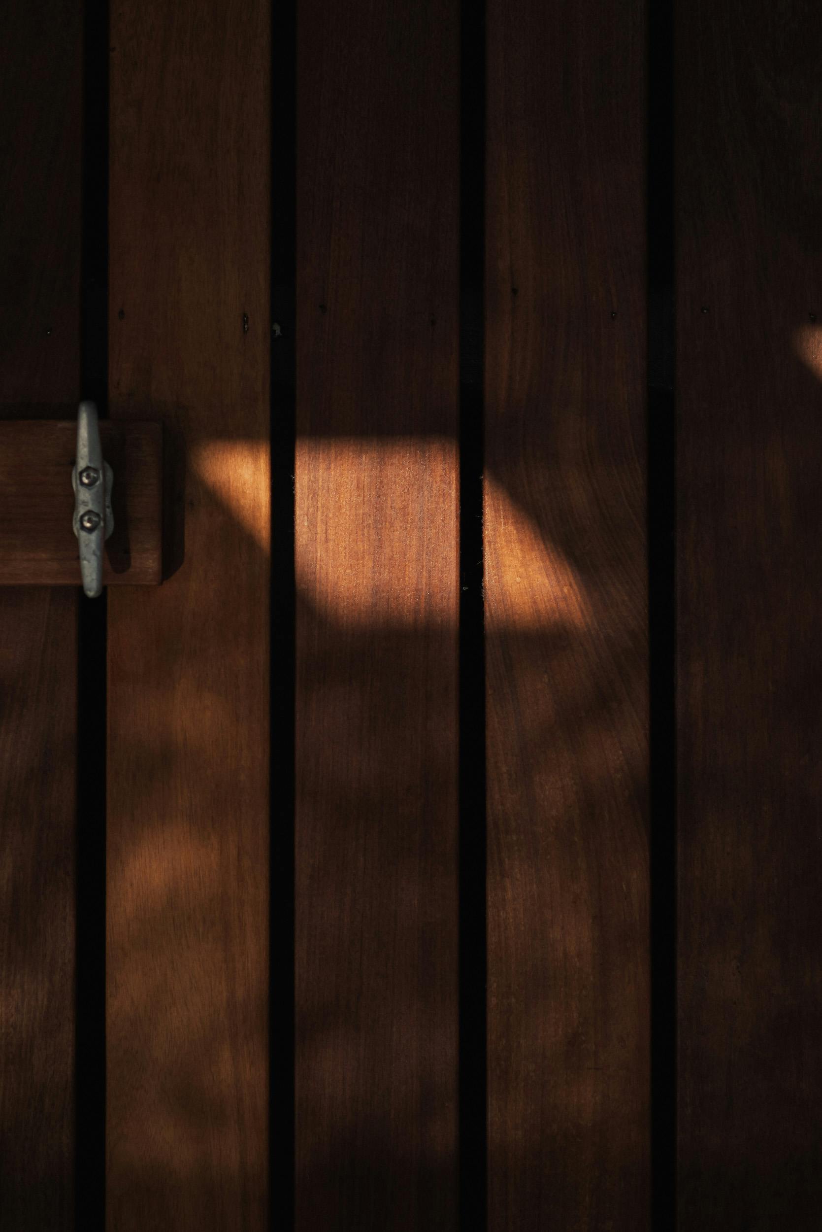 A wooden door with sunlight casting intriguing shadows, creating a textured surface.