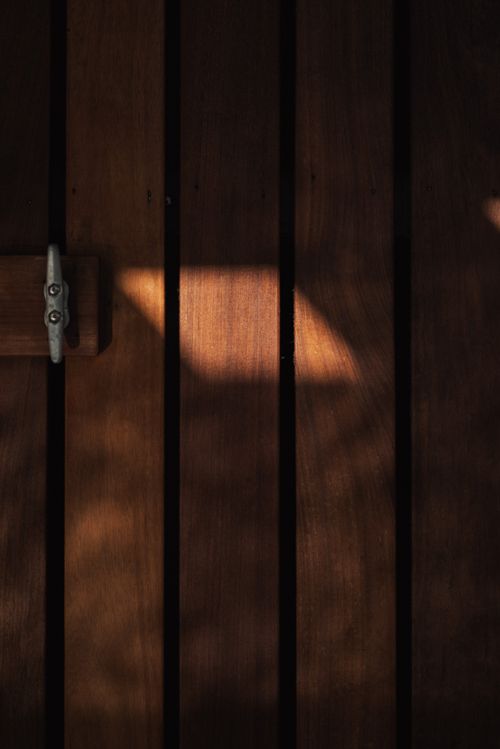 Free A wooden door with sunlight casting intriguing shadows, creating a textured surface. Stock Photo