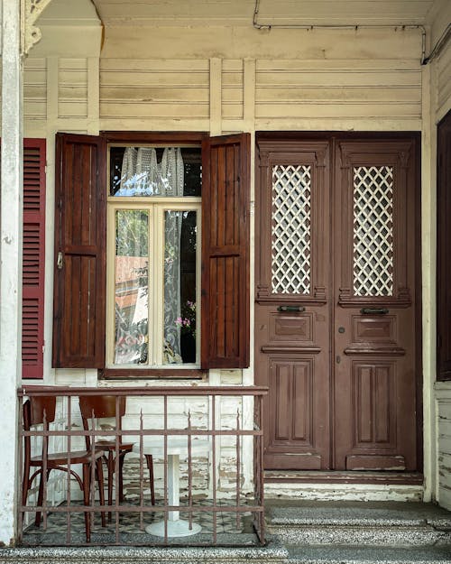 Entrance to an Old House with a Small Porch and Wooden Window Shutters 