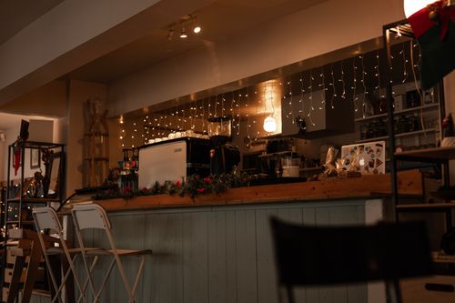 Free Warm and inviting café scene with festive lights and coffee equipment on display. Stock Photo
