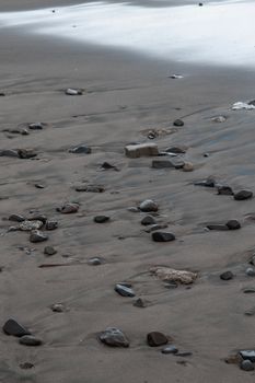 A tranquil beach scene with scattered rocks on wet sandy shore, ideal for nature-themed projects.
