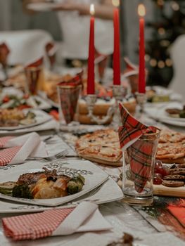 Warm Christmas dining scene with candles, festive tableware, and delicious holiday foods.