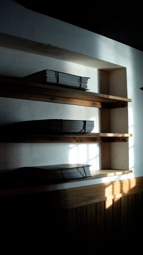 Free Moody shelves with neatly stacked papers in a shadowy room, creating a minimalist aesthetic. Stock Photo