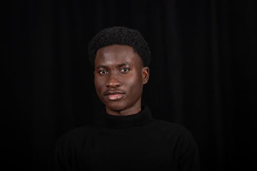 Portrait of a confident black man with short hair against a black background. Ideal for diversity and professional themes.