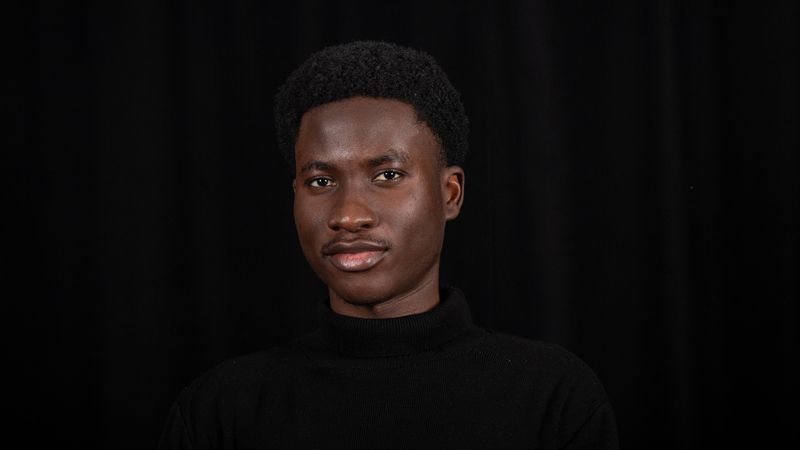 Portrait of a confident black man with short hair against a black background. Ideal for diversity and professional themes.