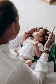 A healthcare professional gently examines a newborn baby indoors.