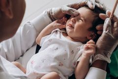 A healthcare professional examines a newborn baby indoors, demonstrating care and attention.