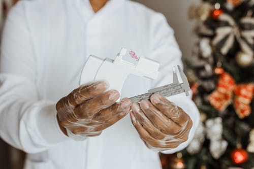 A person holding a box of white gloves and a christmas tree