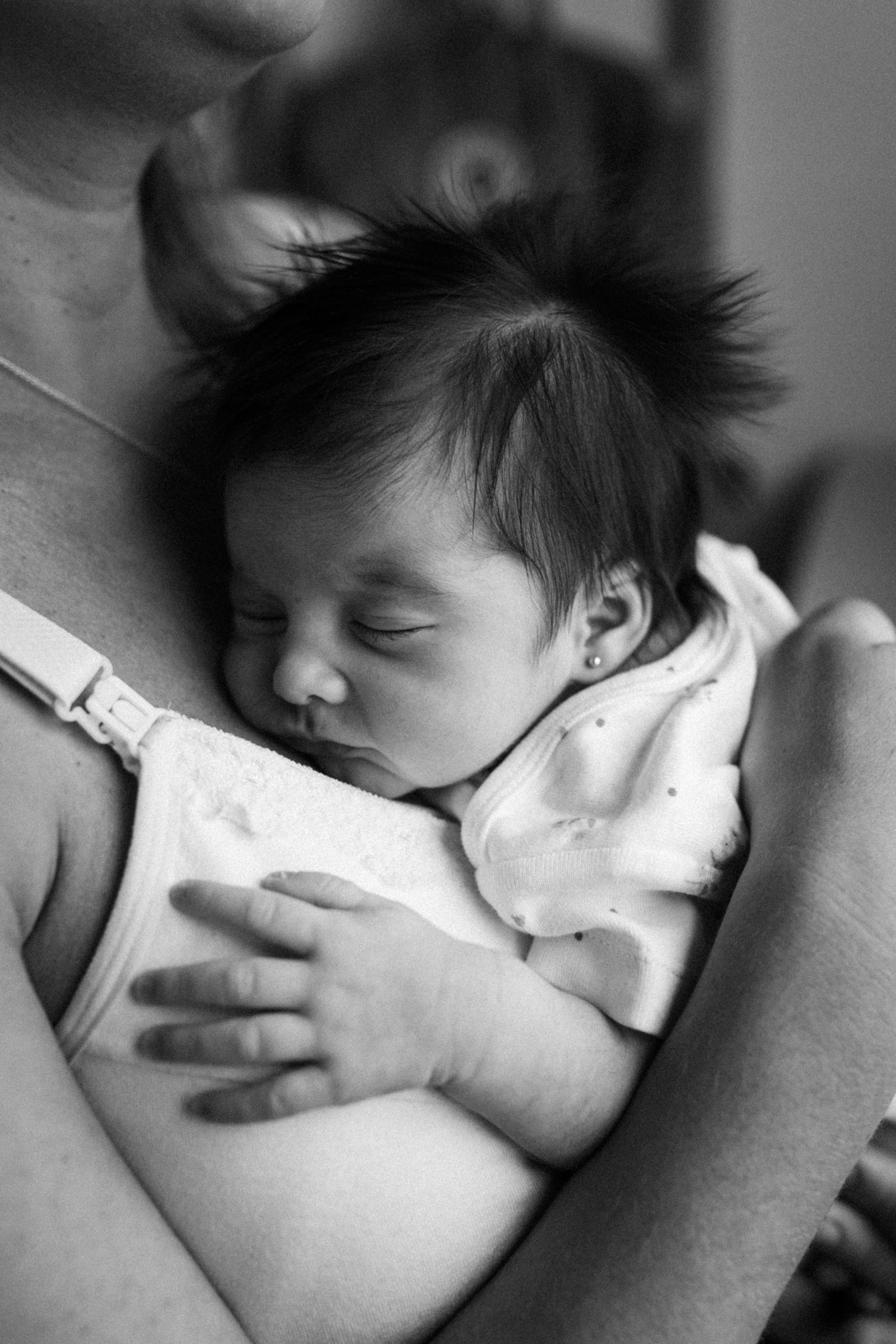 Una nueva madre latina descansando junto a su recién nacido durante el cuarto trimestre, con apoyo continuo de una doula posparto certificada por DNT Network — el rol de la doula posparto se centra en cuidado no médico durante las primeras 12 semanas.